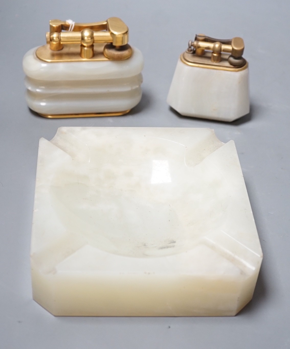 Two Dunhill green onyx table lighters and a matching ashtray, largest lighter 10cms wide